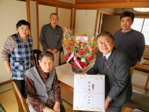 100歳を迎えた澤田トヨミさんと、「祝 百歳」と書かれた熨斗がかかった贈呈品を持つ市長を中心に、後方にご家族の方3名が一緒に写っている写真