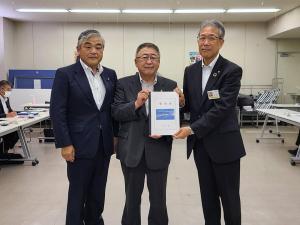 要望書を両手で一緒に持ち正面に向けている市長と関係者の男性1名、その隣に並ぶ男性1名を写した写真