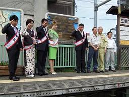 駅のホームで俳優の杉良太郎さん、歌手の伍代夏子さん、山本譲二さん、瀬川瑛子さん、元スピードスケート金メダリストの清水宏保さんと市長と他2人が敬礼をして並んでいる写真
