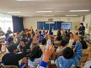 教室の窓側で市長が座って見ている中、交流・懇親会で児童たちが手を挙げている写真