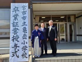 亀岳小学校卒業証書授与式と書かれた看板の横で、市長と卒業生佐藤蓮樹さんと男性が1名並んで撮影した写真