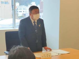 後方に窓ガラスが設置された会議室で、自席から立ち上がった市長が話をしている様子の写真