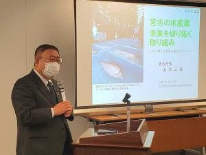 スクリーンに「宮古の水産業未来を切り拓く取り組み」と題した資料が映し出され、檀上でマイクを持ち話をしている市長の写真