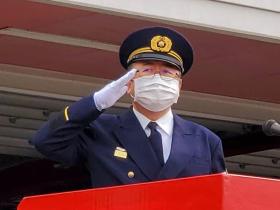 市長が消防団の制服を着て、出初式に参加している団員に向けて敬礼をしている写真