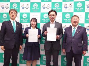 宮古市のバックパネルの前で、地域おこし協力隊に任命され任命書を持った伊藤さんと中村さんを中央に、市長と副市長が横一列に並んでいる写真