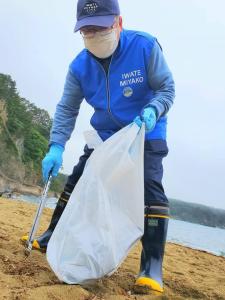 海水浴場の砂浜でゴミ拾いをする様子の市長の写真