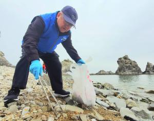 海岸でごみを拾っている様子の市長の写真