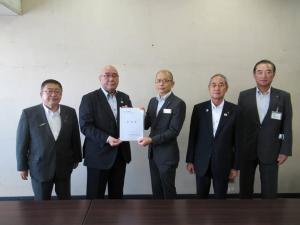 左から市長、要望書を一緒に持つ男性2名、その隣で直立して並ぶ男性2名が記念撮影をしている写真