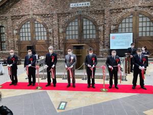 レッドカーペットの上に横一列に並び、テープカットをする様子の市長を含めた7名の官憲者達の写真