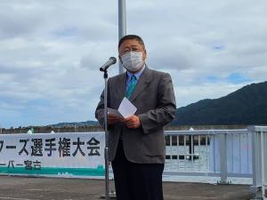 宮古湾の脇でスタンドマイクの前に立ち手紙を両手に広げ話している様子の市長の写真