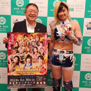 バックパネルの前で試合開催のポスターを持つ市長と女子プロレスラーMIRAI(ミライ)選手の記念写真