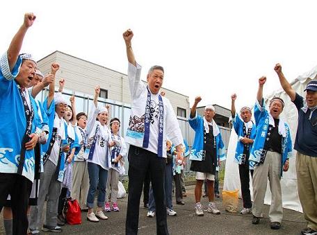 白い半被をきた男性の回りに青色の半被を着た東京宮古同郷会の方々が集まり片手を上にあげ気合をいれている写真