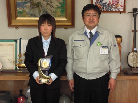 スーツを着たフルマラソン女子で優勝した大久保和美さんがトロフィーを持ち市長と記念撮影している写真