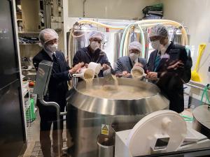 クラフトビールを製造している部屋で、帽子をかぶった市長含めた男性4名がタンクに入っているビールを桶ですくっている写真