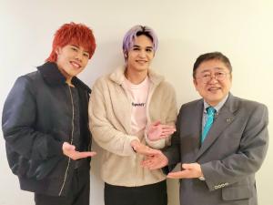 右側に市長、真ん中に紫っぽい色の髪型の男性、左に赤茶色の髪型をした男性の3名で並んで記念撮影をしている写真
