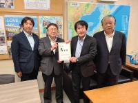 日本地図や大きなポスターが貼られた室内で、国土交通省の丹羽克彦道路局長と市長が要望書を一緒に持ち、宮古市議会の橋本久夫議長と宮古商工会議所の大坂文人副会頭が横一列に並んでいる写真