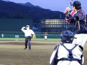 帽子を被り、ワイシャツ姿の市長が、始球式でマウンド手前からボールを投げようしている写真