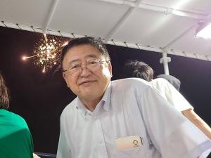 打ち上げられた花火に背を向け笑顔を浮かべる市長の写真