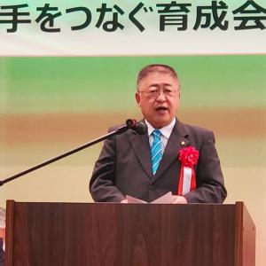 「手をつなぐ育成会」と書かれた横断幕の前に置かれた演台の前で演説している様子の市長の写真