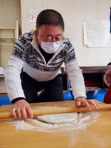 麺棒で平たく広げられたそば粉を伸ばしている様子の市長の写真