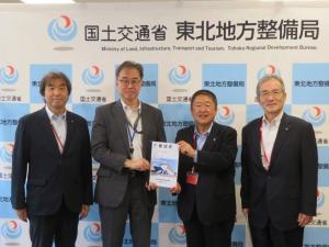 「国土交通省 東北地方整備局」のバックパネルの前で、市長と男性で要望書を持ち、その両脇に男性1名ずつが立っている写真