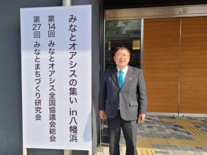 会場入り口に設置された「みなとオアシスの集いin八幡浜」と書かれた看板の横に立つ市長の写真