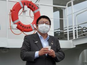 船の前で、グラスを手に持っている市長の写真