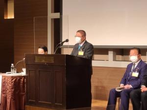 アクリルパネルが前面に設置された演台の前で演説をしている様子の市長の写真