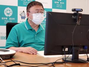 カメラが取り付けられたパソコンモニターの前に座り、画面を真剣に見つめる市長の写真