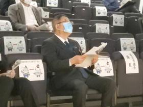 市長が客席に座って資料を見ながら、報告会を聞いている写真