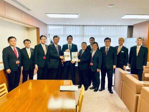 市長含む関係者11名が並び、中央付近にいる市長ら3名の男性が要望書を持っている写真