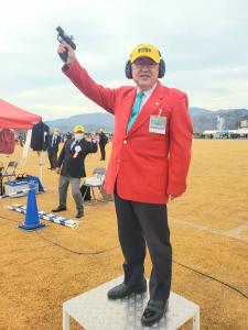黄色のキャップを被り耳あてをし、スターターピストル持った右手を上にあげ台の上に乗った市長がスタートの合図を行っている様子の写真