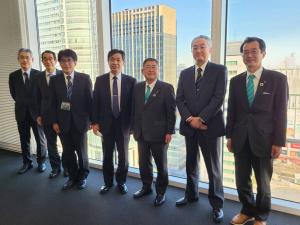 高層ビルが一望できる室内で、市長を含む男性7名が立ち、並んでいる写真