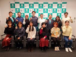 市長と副市長、インターンに来ている大学生たちがそれぞれ右手でガッツポーズをとり、 2列に並んで撮影した写真