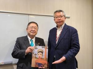 女性の絵が書かれた絵画を手に持つ市長と、糸川雄介日本・韓国支社長がその絵画に手を添えている写真