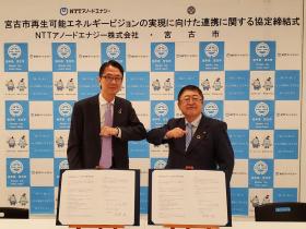 NTTアノードエナジー株式会社の代表と市長がそれぞれが署名した協定書を前において、肘タッチをしている写真