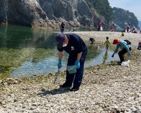 海水浴場の浜でゴミ拾いをする様子の市長と参加者たちの写真