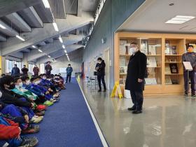 競技場内の室内で強化合宿に参加している選抜された中学生の前で、市長があいさつをしている写真