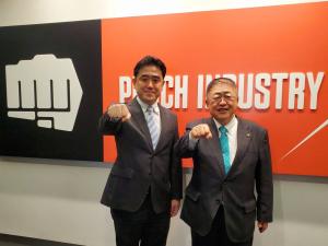 パンチ工業株式会社のロゴの前で、右こぶしをグーにして前につきだし、同じポーズをしている市長と森久保哲司代表取締役社長の写真