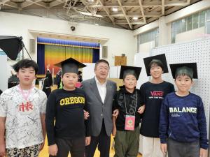 博士帽を被った4名の児童と市長と書かれたネームプレートを下げた児童と市長が並んで撮影した写真
