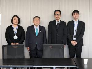 壁に背をつけ起立して正面を向く女性1名と、市長を含む男性3名が横一列に並んでいる記念写真