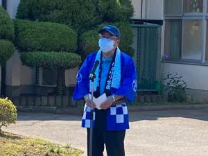 青い法被を着て帽子を被り首からハチマキを掛けた市長がスタンドマイクの前で話をしている様子の写真