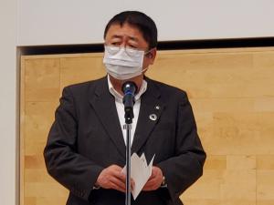 お腹の前で両手で持った資料を広げ、首を斜め前に向け話をしている様子の市長の写真