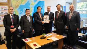 国土交通省内で吉岡幹夫道路局長に道路の整備促進の要望書を渡しているところに同行した市長を含めた岩手県道路整備促進期成同盟会10団体の方も並んで6人で撮影した写真