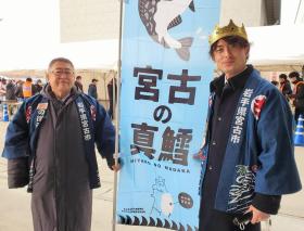 襟字に岩手県宮古市と書かれた法被を着た市長と金色の冠を被り、同じ法被を着た魚市場関係の方が宮古の真鱈と書かれた幟旗を持っている写真