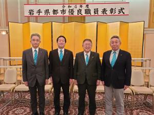 「令和4年度岩手県都市優良職員表彰式」と書かれた横断幕と金屏風の前に市長含めた男性4名が立ち並んでいる写真