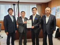大きなポスターがが貼られた室内で、経済産業省の岩田和親大臣政務官と市長が要望書を一緒に持ち、宮古市議会の橋本久夫議長と宮古商工会議所の大坂文人副会頭が横一列に並んでいる写真