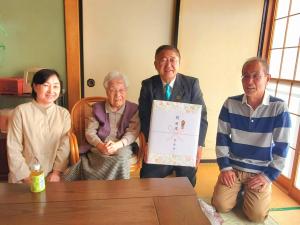 満100歳になった西ケ丘の中村和子さんと、熨斗が貼られた記念品をもつ市長を中心に女性と男性が1人ずつ両側に座り笑顔で写る記念写真
