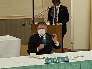 長机の椅子に座り、マイクを持って発言している市長の写真