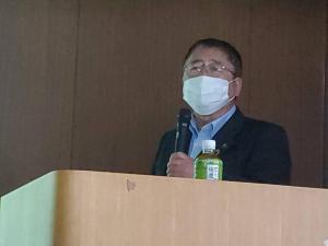 ペットボトルのお茶が置かれた台の前で左手にマイクを持ち話をしているようすの市長の写真